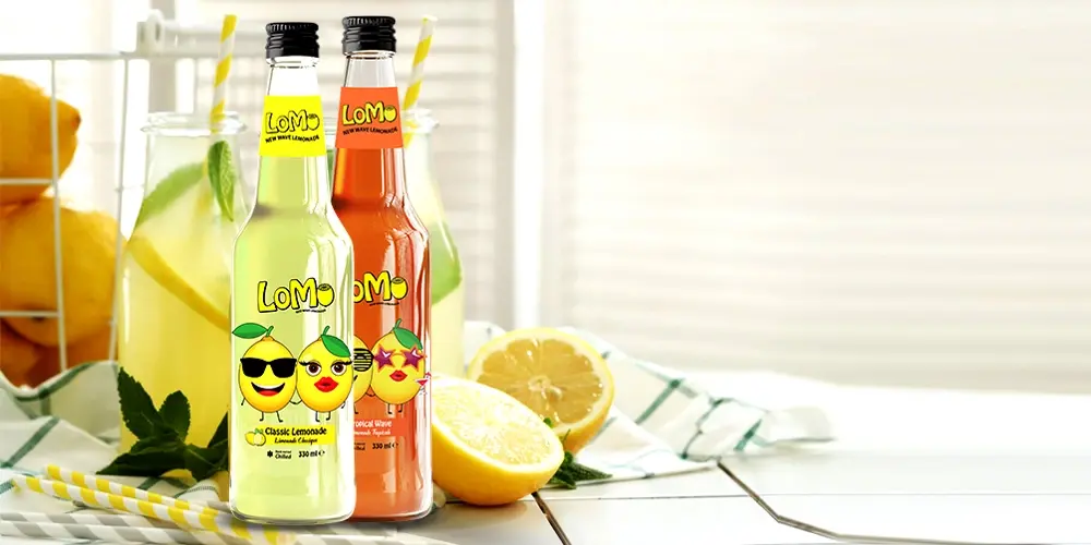 Lomo lemonade bottles featuring Classic Lemonade and Tropical Wave flavors, perfect for a refreshing citrus experience.